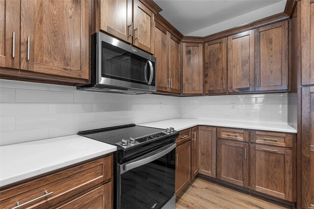 12 Creekside Way, Cape Girardeau, MO 63701 - kitchen featuring stainless steel microwave, electric range, decorative backsplash, light countertops, and light wood finished floors