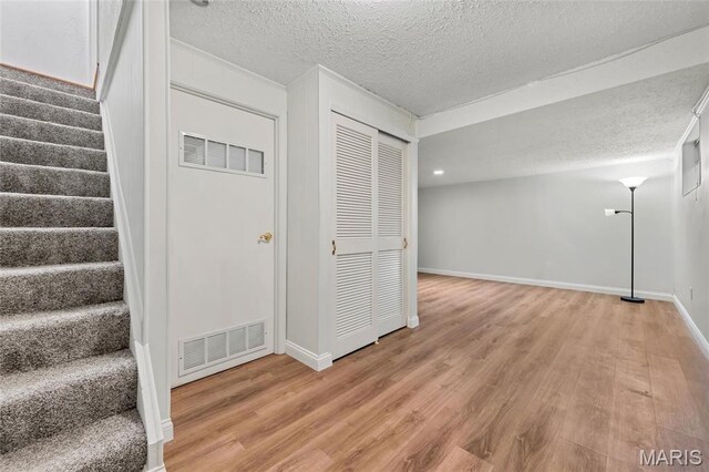 13355 Land O Woods Dr, Saint Louis, MO 63141 - basement with light wood finished floors, a textured ceiling, stairs, and baseboards