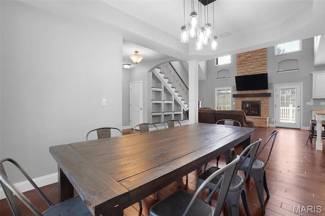 9336 Excelsior Rd, Gerald, MO 63037 - dining space featuring stairway, a stone fireplace, hardwood / wood-style floors, baseboards, and ornate columns