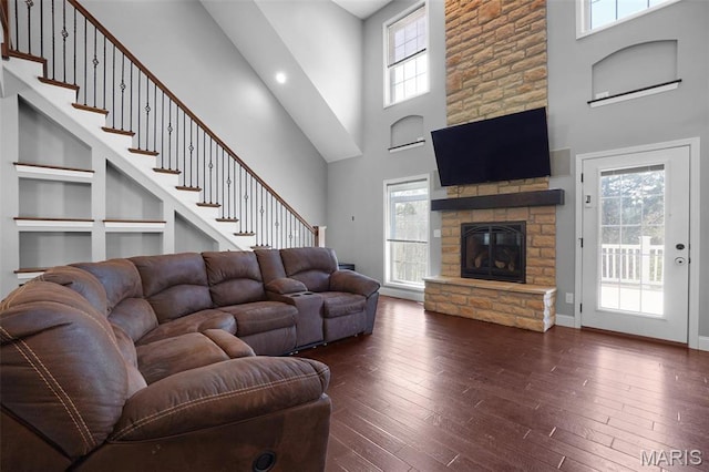 9336 Excelsior Rd, Gerald, MO 63037 - living room featuring a towering ceiling, healthy amount of natural light, dark wood-style floors, a stone fireplace, and built in features