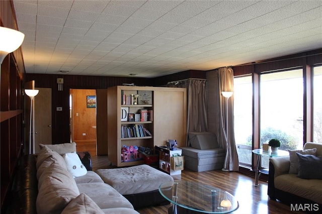 living area featuring healthy amount of natural light, wood finished floors, and wooden walls