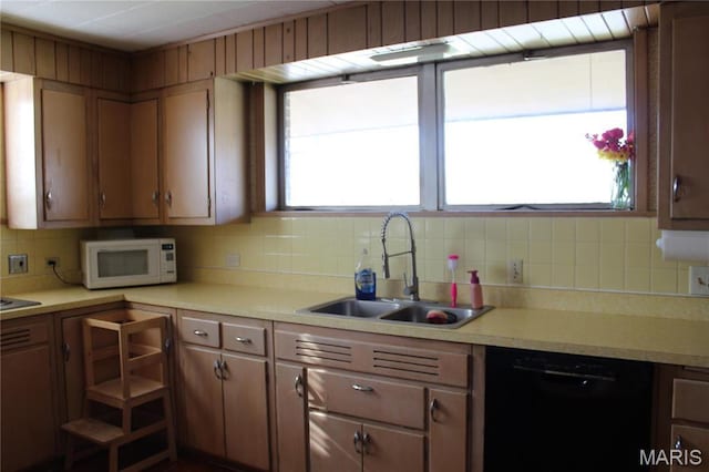kitchen featuring black dishwasher, white microwave, a sink, and backsplash