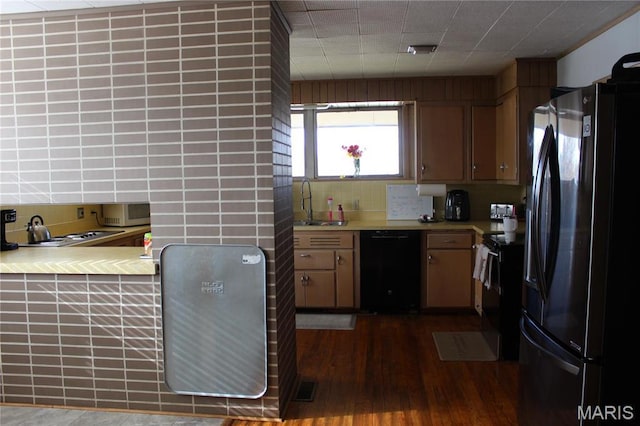 kitchen featuring black appliances, decorative backsplash, dark wood-style flooring, and a sink