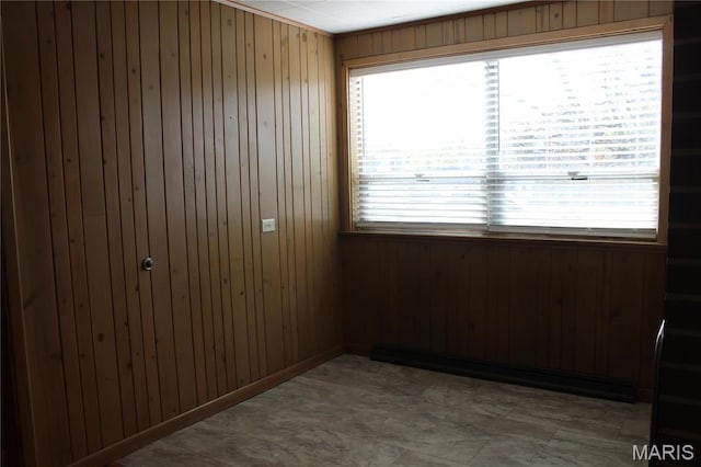 unfurnished room featuring wooden walls and plenty of natural light