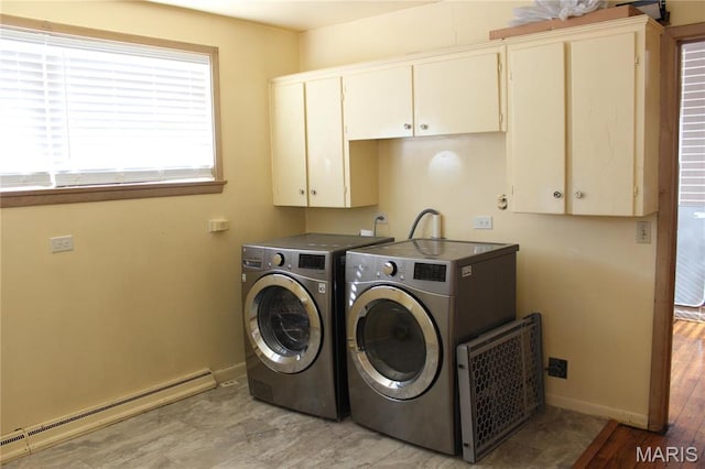 clothes washing area with a baseboard heating unit, cabinet space, washer and dryer, and baseboards