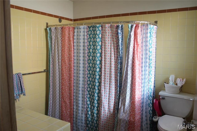 full bathroom with tile walls, toilet, and curtained shower