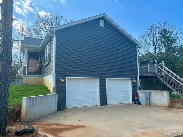 view of home's exterior with an attached garage, concrete driveway, and stairway