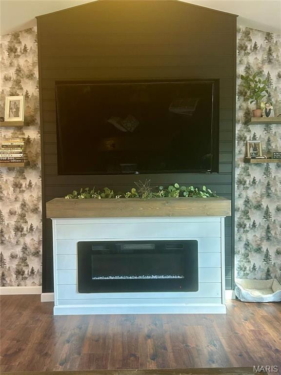 detailed view of wallpapered walls, wood finished floors, a fireplace, and baseboards