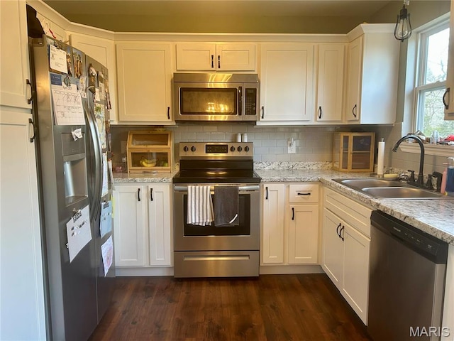 kitchen with stainless steel appliances, a sink, white cabinetry, backsplash, and dark wood finished floors