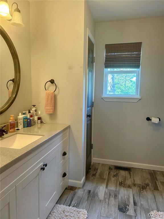 bathroom with wood finished floors, vanity, and baseboards