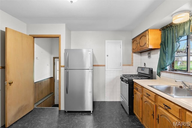 8900 Southview Ln, Saint Louis, MO 63123 - kitchen featuring stainless steel appliances, a sink, brown cabinets, light countertops, and a wainscoted wall