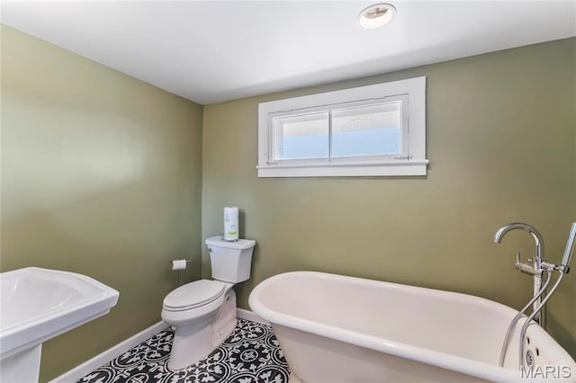 876 W State St W, Jacksonville, IL 62650 - bathroom featuring baseboards, a soaking tub, toilet, and a sink