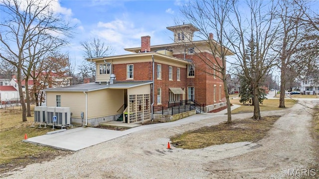 876 W State St W, Jacksonville, IL 62650 - rear view of property featuring a chimney, brick siding, and cooling unit