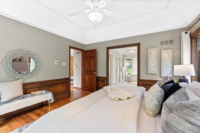 13596 Kings Glen Dr, Saint Louis, MO 63131 - bedroom featuring a tray ceiling, wood finished floors, wainscoting, and ceiling fan