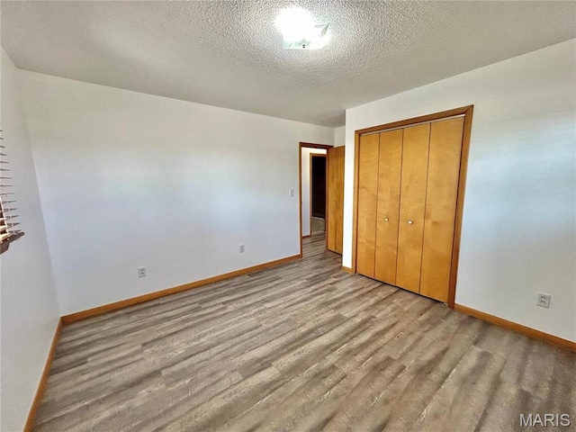 1101 S Mildred Blvd, Salem, MO 65560 - unfurnished bedroom with baseboards, wood finished floors, a closet, and a textured ceiling