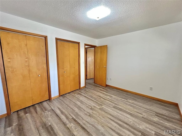 1101 S Mildred Blvd, Salem, MO 65560 - unfurnished bedroom featuring multiple closets, wood finished floors, baseboards, and a textured ceiling
