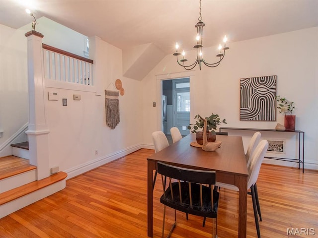 dining space with light wood-type flooring, a chandelier, stairs, and baseboards