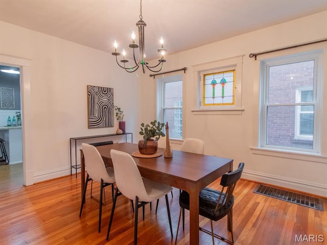 dining area featuring light wood finished floors, a chandelier, and baseboards