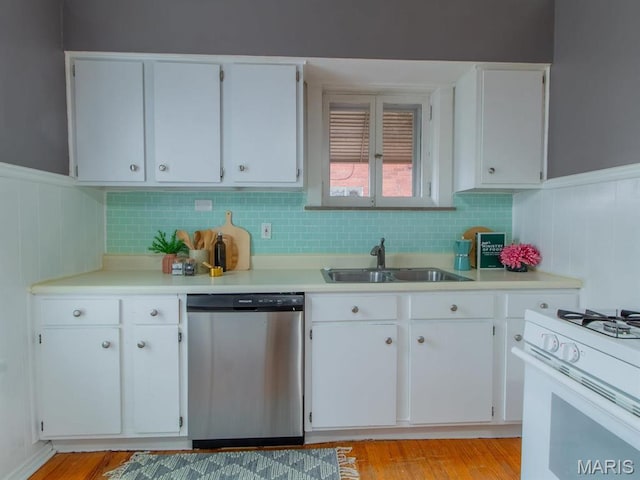 kitchen featuring dishwasher, a sink, white range with gas cooktop, light countertops, and a wainscoted wall