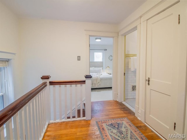 corridor with an upstairs landing and wood finished floors