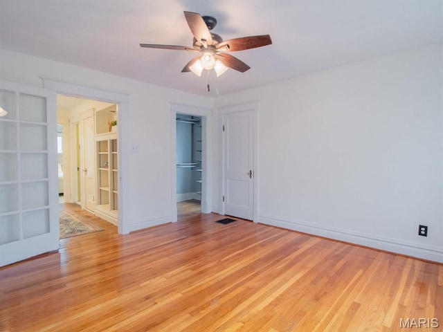 empty room with ceiling fan, light wood-style floors, and baseboards