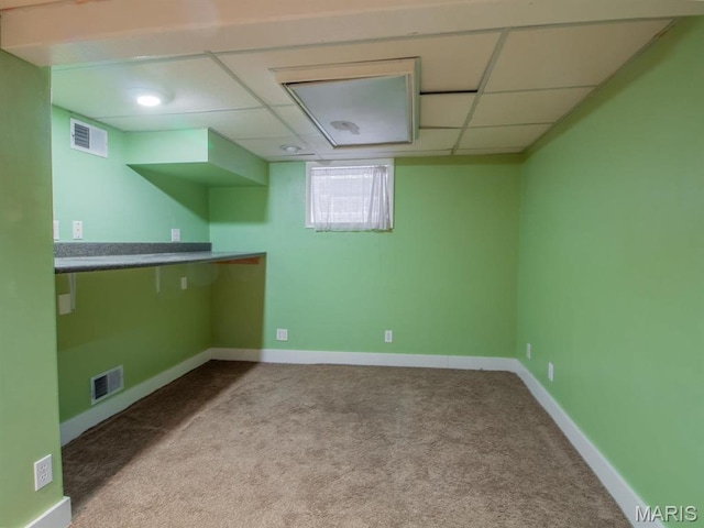 below grade area with carpet, baseboards, and a paneled ceiling