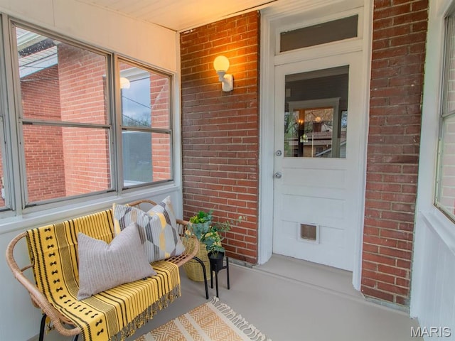 doorway to property with a porch and brick siding