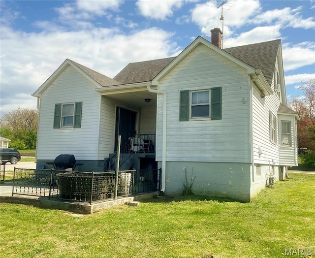 109 N Oak St, Rolla, MO 65401 - back of property featuring a shingled roof, a chimney, and a lawn