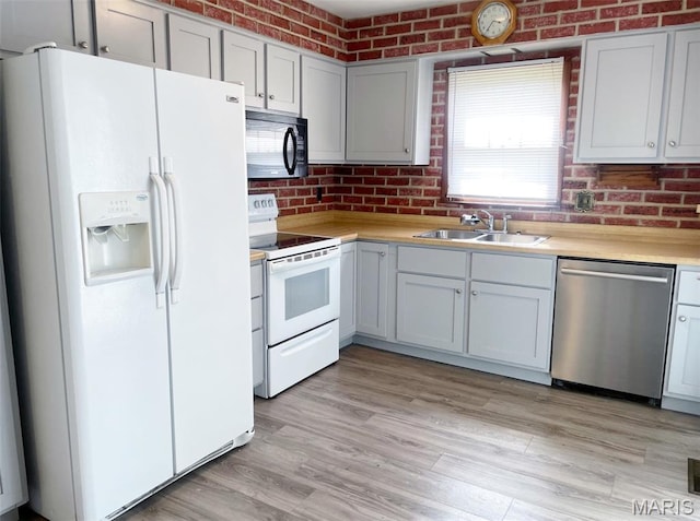 109 N Oak St, Rolla, MO 65401 - kitchen with white appliances, a sink, light countertops, brick wall, and light wood-style floors