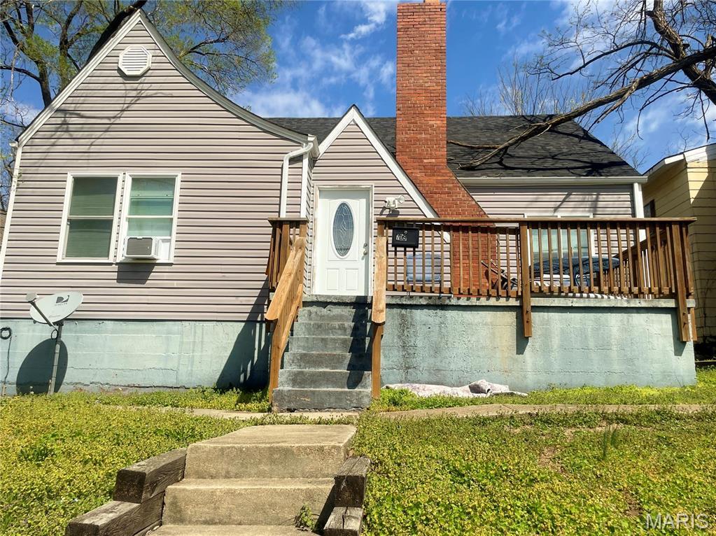 view of front of property featuring a chimney, cooling unit, and a front lawn