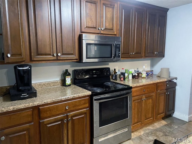 709 E 10th St, Rolla, MO 65401 - kitchen with stainless steel microwave, range with electric stovetop, and baseboards