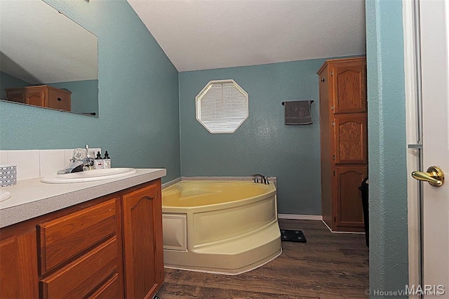 301 Kimberly Dr, Scott City, MO 63780 - bathroom with wood finished floors, vaulted ceiling, a bath, vanity, and a textured wall