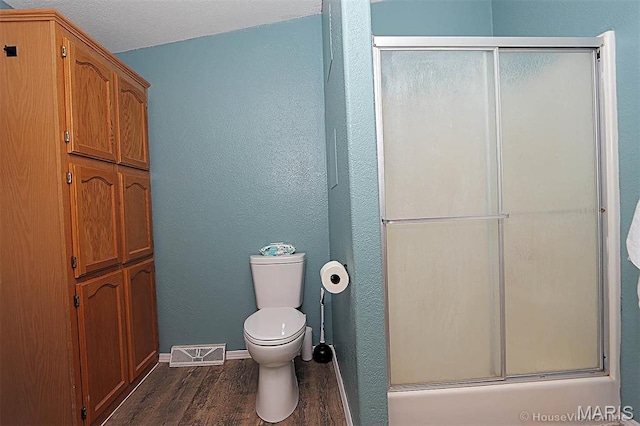 301 Kimberly Dr, Scott City, MO 63780 - bathroom with wood finished floors, toilet, baseboards, shower / bath combination with glass door, and a textured wall
