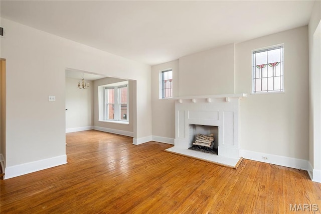 6026 Waterman Blvd Unit 1W, Saint Louis, MO 63112 - unfurnished living room featuring a chandelier, wood finished floors, baseboards, and a fireplace