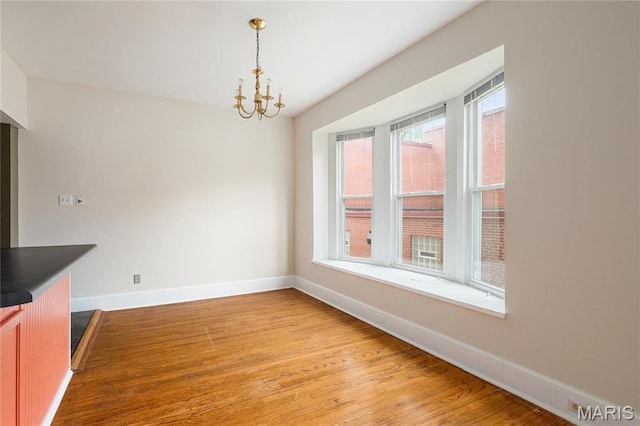 6026 Waterman Blvd Unit 1W, Saint Louis, MO 63112 - unfurnished dining area with baseboards, light wood-style flooring, and a chandelier