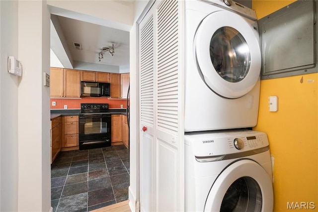 6026 Waterman Blvd Unit 1W, Saint Louis, MO 63112 - laundry room featuring stacked washer / drying machine, dark stone finish floors, and track lighting