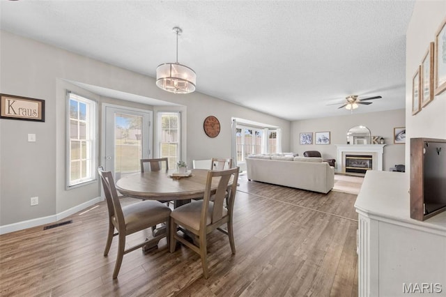 11 Country Crossing Estates Dr, Saint Peters, MO 63376 - dining area featuring a textured ceiling, a ceiling fan, wood finished floors, a glass covered fireplace, and a chandelier