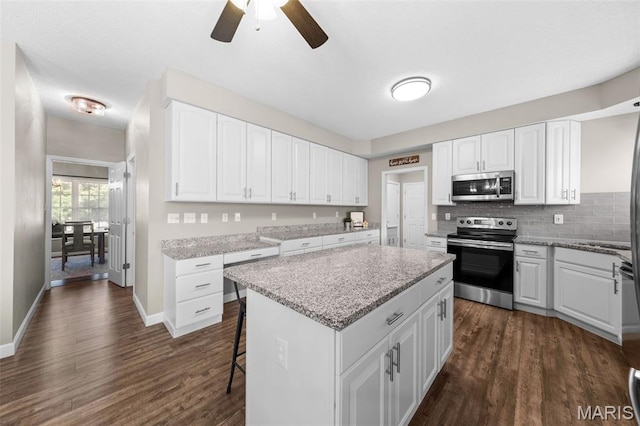 11 Country Crossing Estates Dr, Saint Peters, MO 63376 - kitchen featuring appliances with stainless steel finishes, a kitchen island, dark wood-type flooring, white cabinets, and a ceiling fan