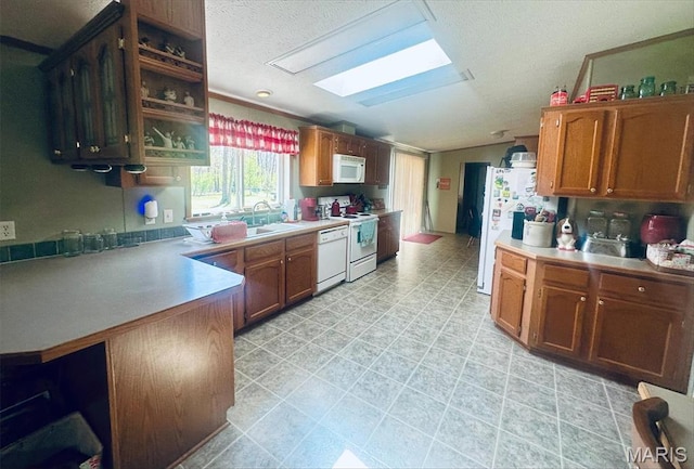 kitchen featuring white appliances, lofted ceiling, a skylight, light countertops, and a textured ceiling
