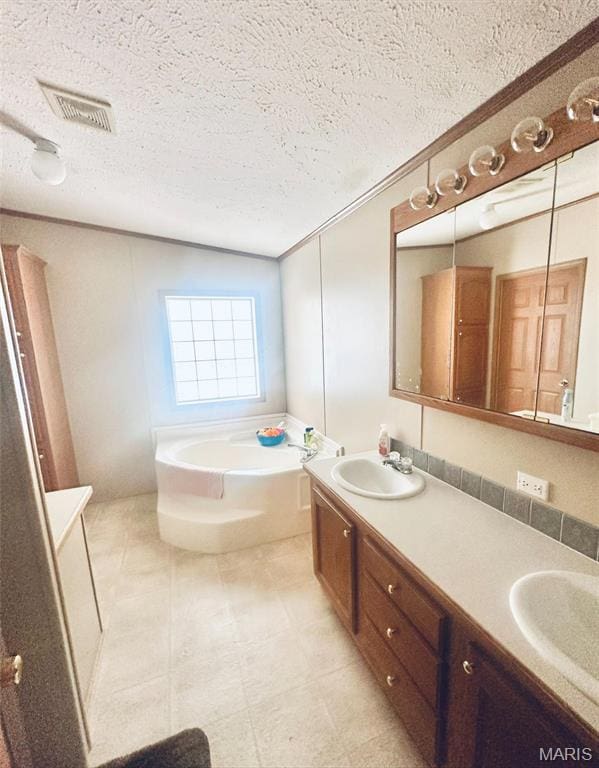 bathroom with double vanity, a garden tub, and a textured ceiling