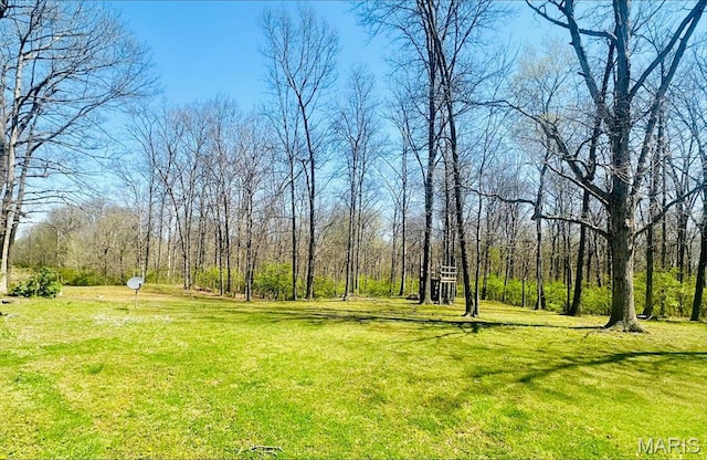 view of grassy yard featuring a view of trees