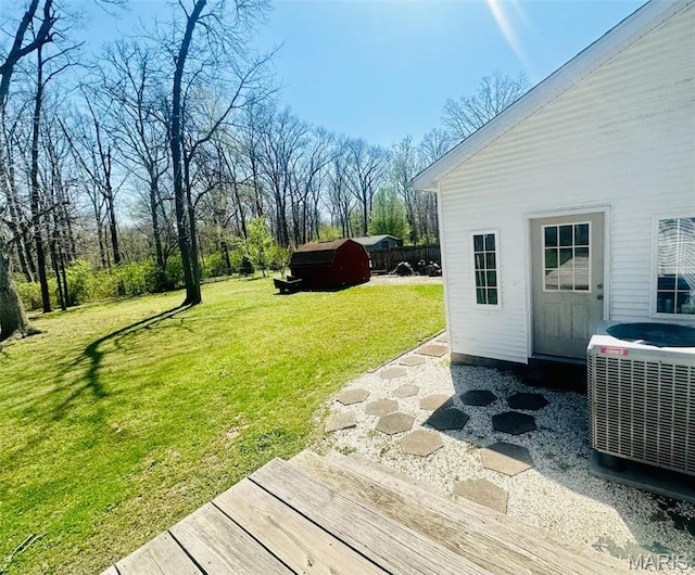 view of grassy yard with central AC unit, an outbuilding, and a storage unit