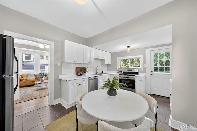 837 Tuxedo Blvd, Saint Louis, MO 63119 - kitchen with stainless steel appliances, white cabinets, light countertops, decorative backsplash, and dark tile patterned flooring