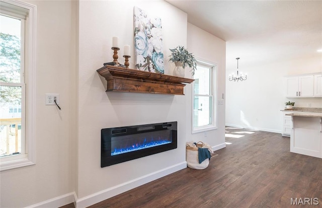 235 Sunny Dr, Rolla, MO 65401 - living room featuring dark wood-style flooring, healthy amount of natural light, a glass covered fireplace, and a chandelier