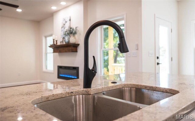 235 Sunny Dr, Rolla, MO 65401 - kitchen with a sink, light stone counters, a glass covered fireplace, and recessed lighting