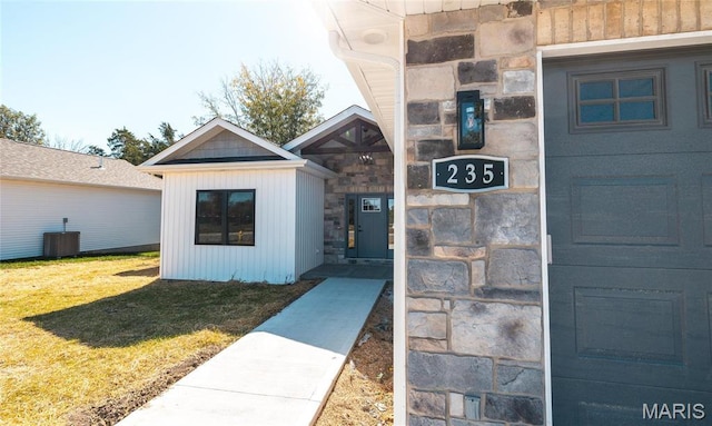 235 Sunny Dr, Rolla, MO 65401 - doorway to property with stone siding, a yard, central air condition unit, and board and batten siding
