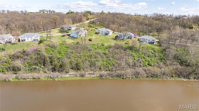 drone / aerial view of a nearby body of water and a forest