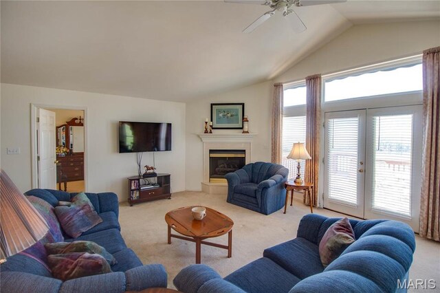 carpeted living area featuring lofted ceiling, a ceiling fan, and a glass covered fireplace