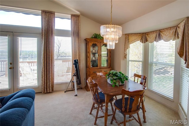 dining space with lofted ceiling, light colored carpet, and a chandelier