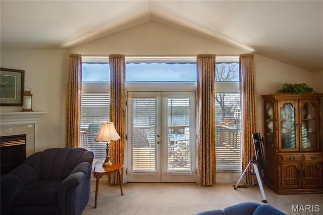 doorway to outside featuring vaulted ceiling, light colored carpet, french doors, and a fireplace
